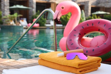 Photo of Beach accessories on sun lounger, inflatable ring and float near outdoor swimming pool at luxury resort