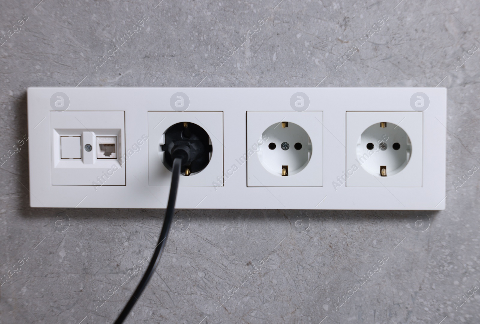 Photo of Power sockets and electric plug on grey wall