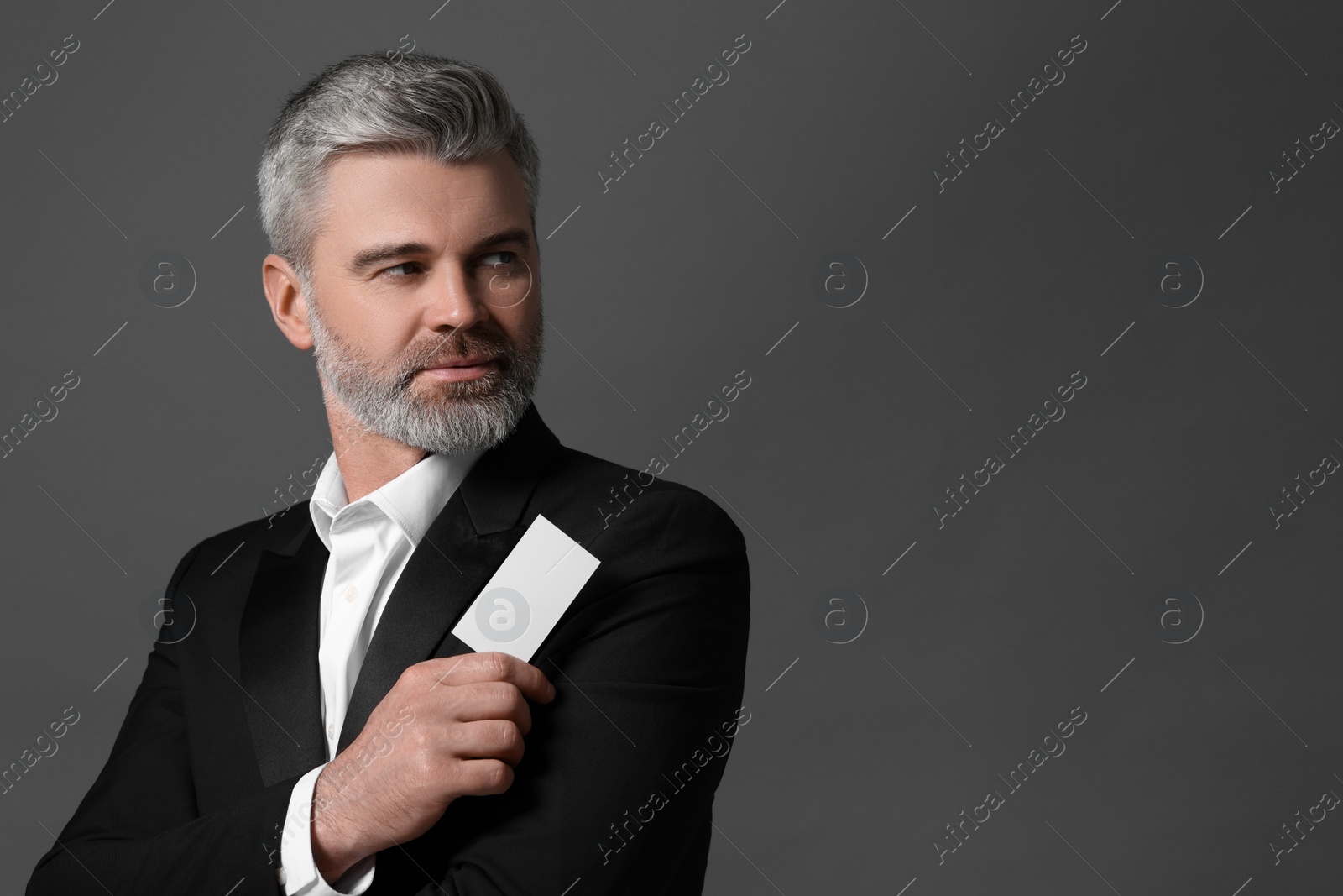 Photo of Handsome businessman holding blank business card on grey background. Space for text