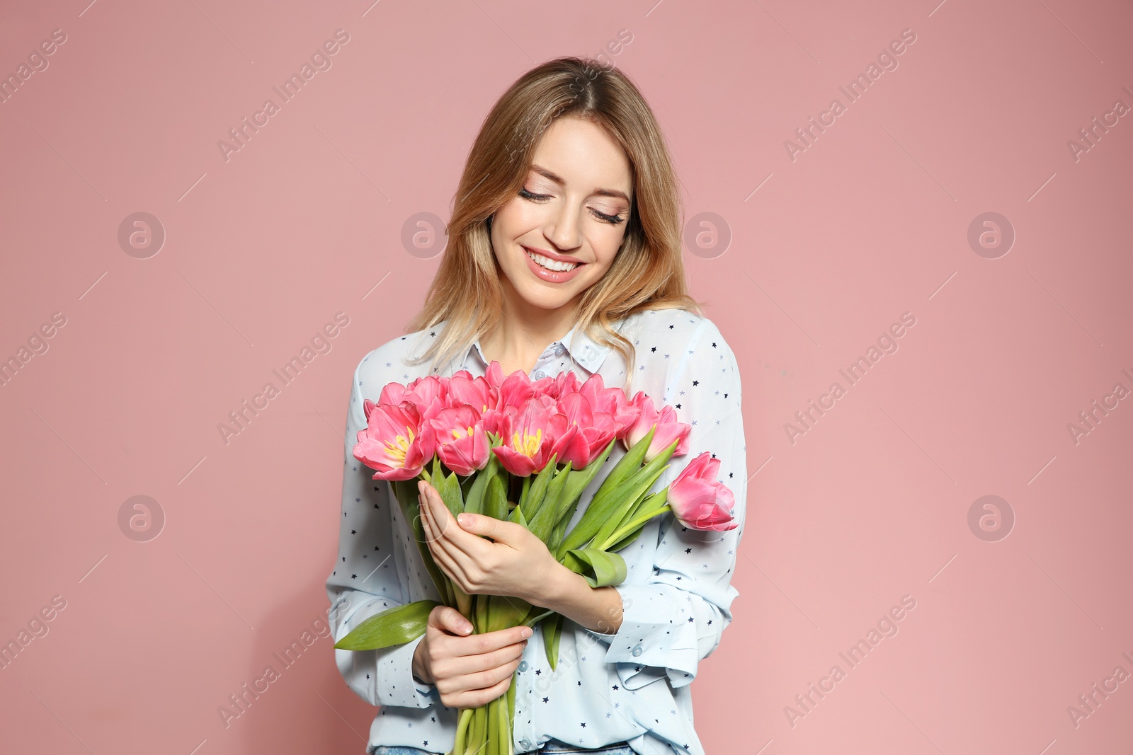 Photo of Portrait of beautiful smiling girl with spring tulips on pink background. International Women's Day