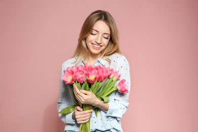 Portrait of beautiful smiling girl with spring tulips on pink background. International Women's Day