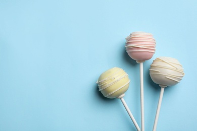 Photo of Sweet cake pops on light blue background, flat lay. Space for text