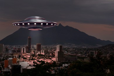 Image of Alien spaceship emitting light over buildings in city. UFO, extraterrestrial visitors