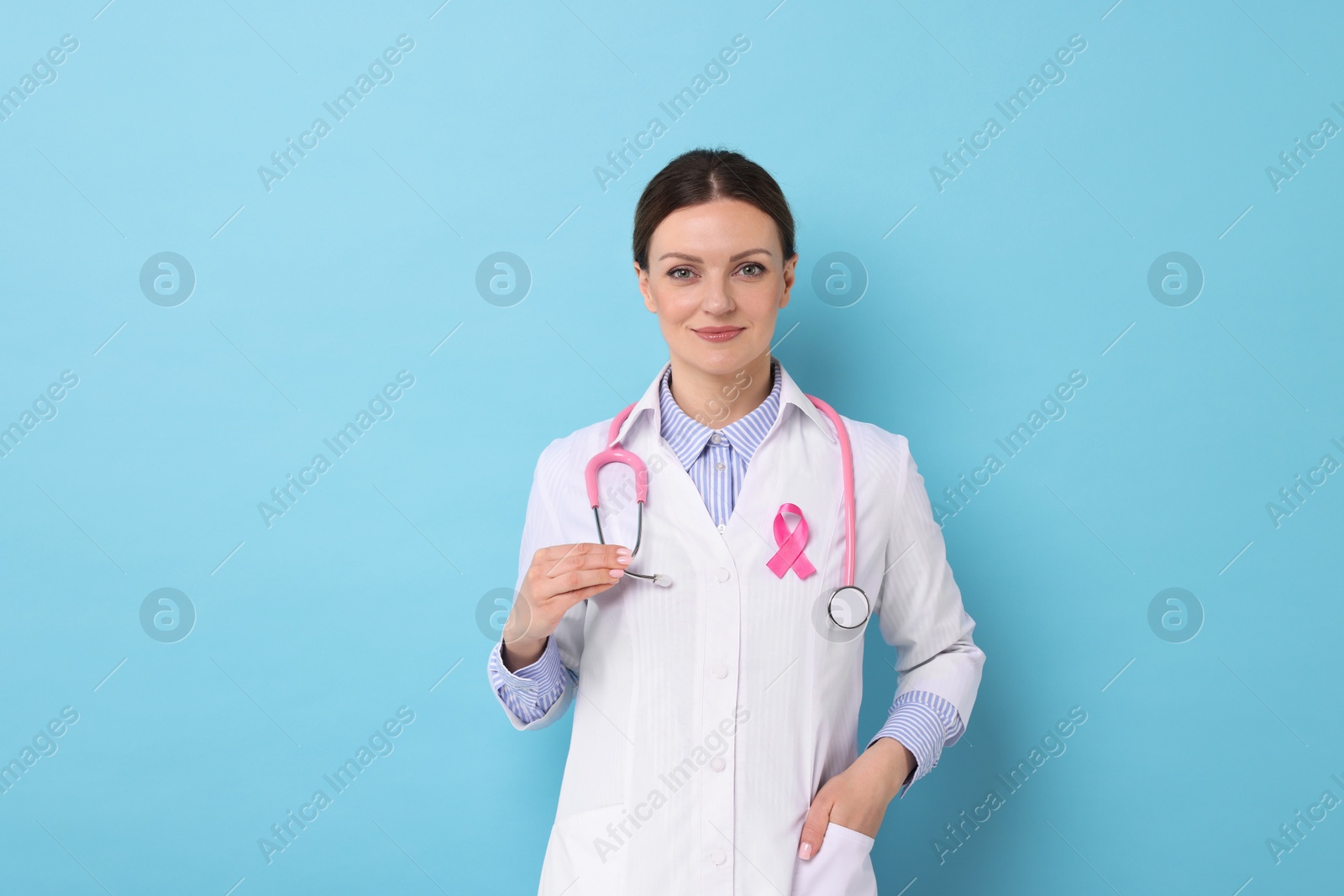 Photo of Mammologist with pink ribbon on light blue background. Breast cancer awareness