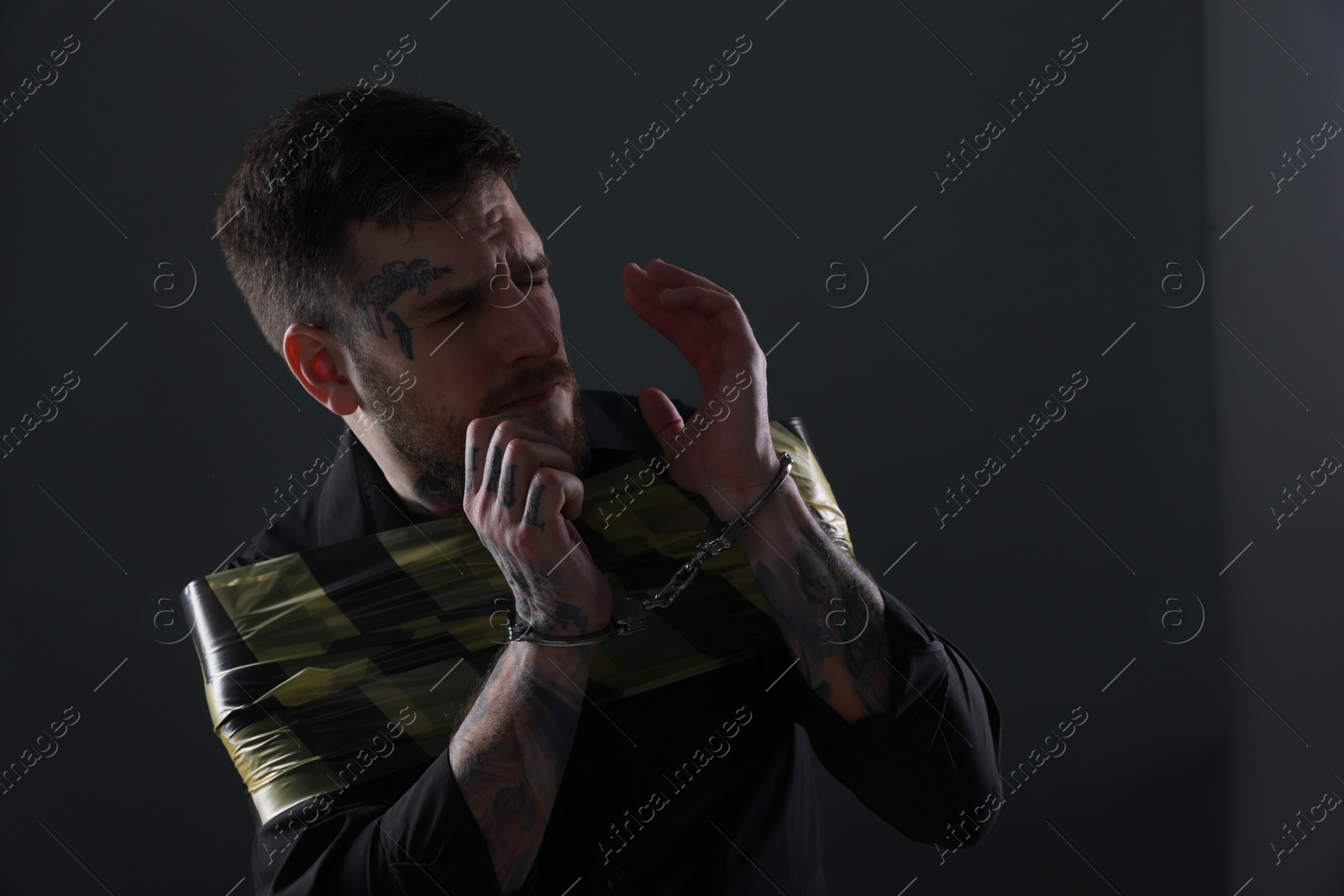 Photo of Scared man taped up and taken hostage on dark background. Space for text