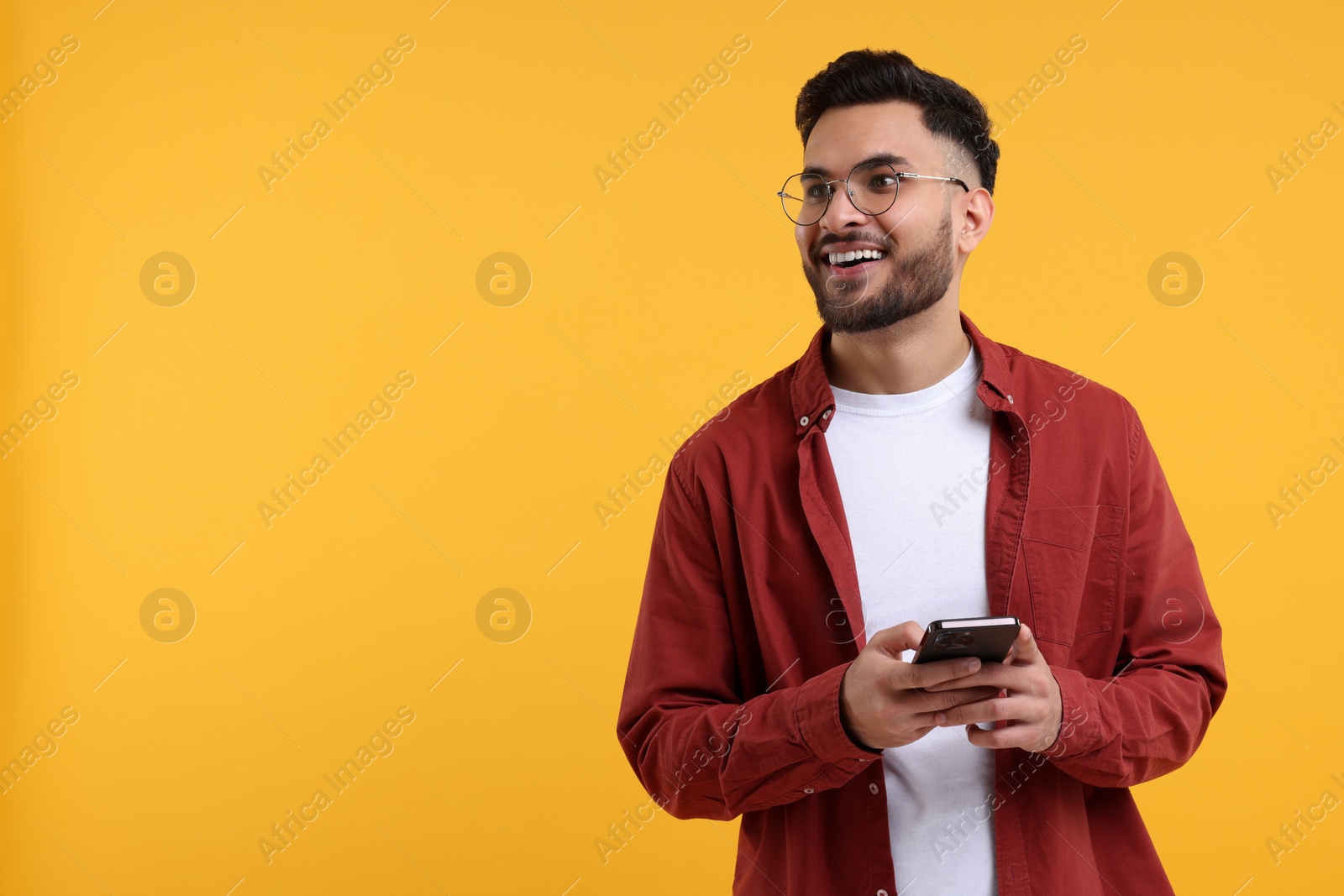 Photo of Happy young man using smartphone on yellow background, space for text