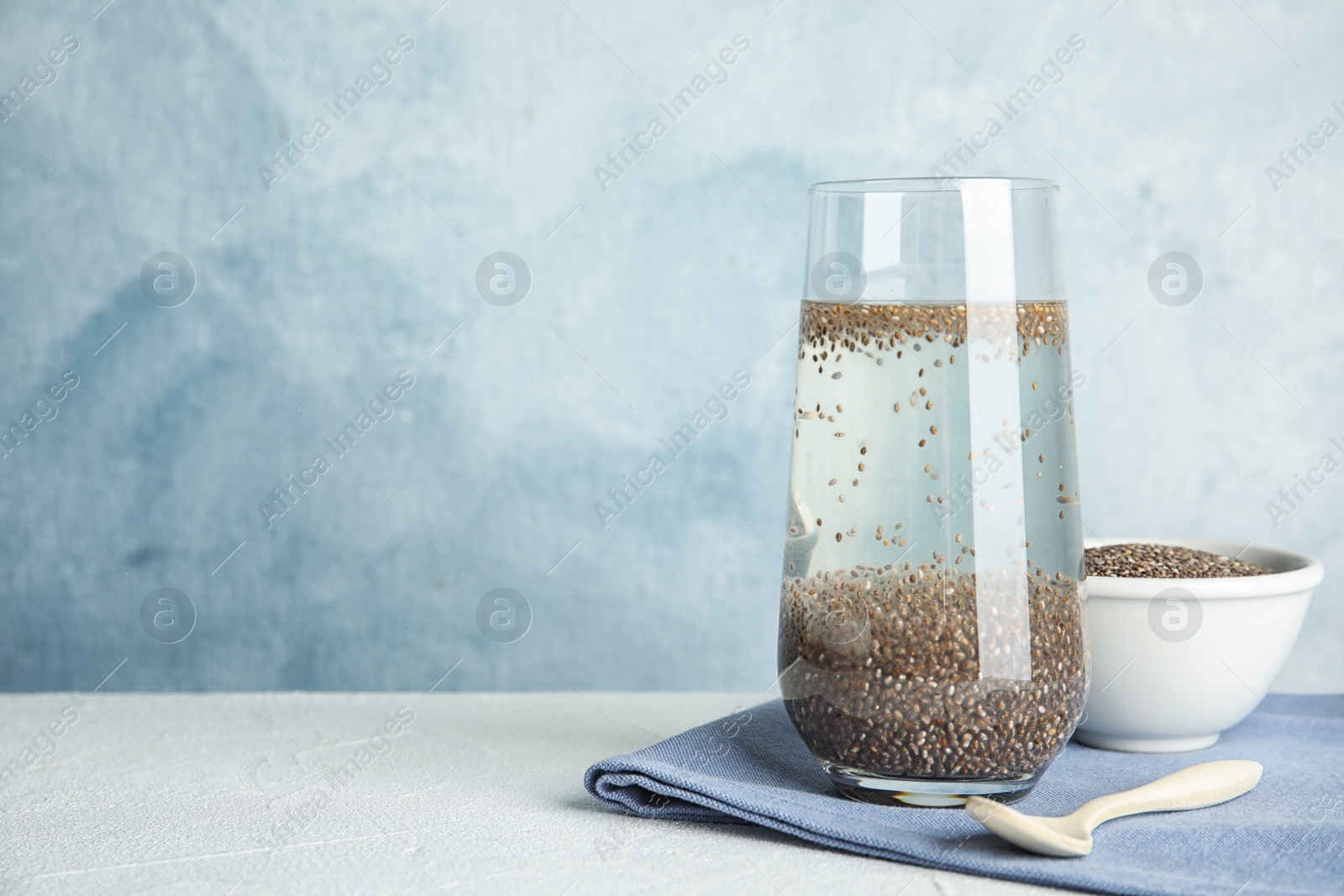 Photo of Composition with glass of water and chia seeds on table against color background, space for text