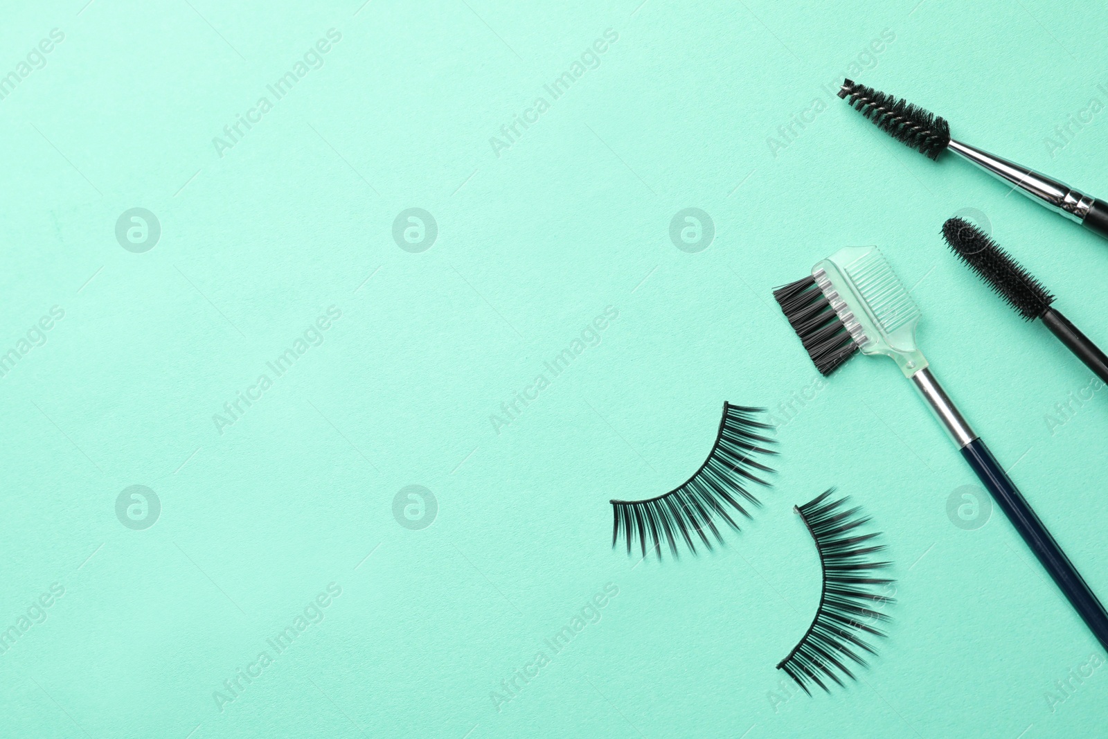 Photo of False eyelashes and brushes on turquoise background, flat lay. Space for text