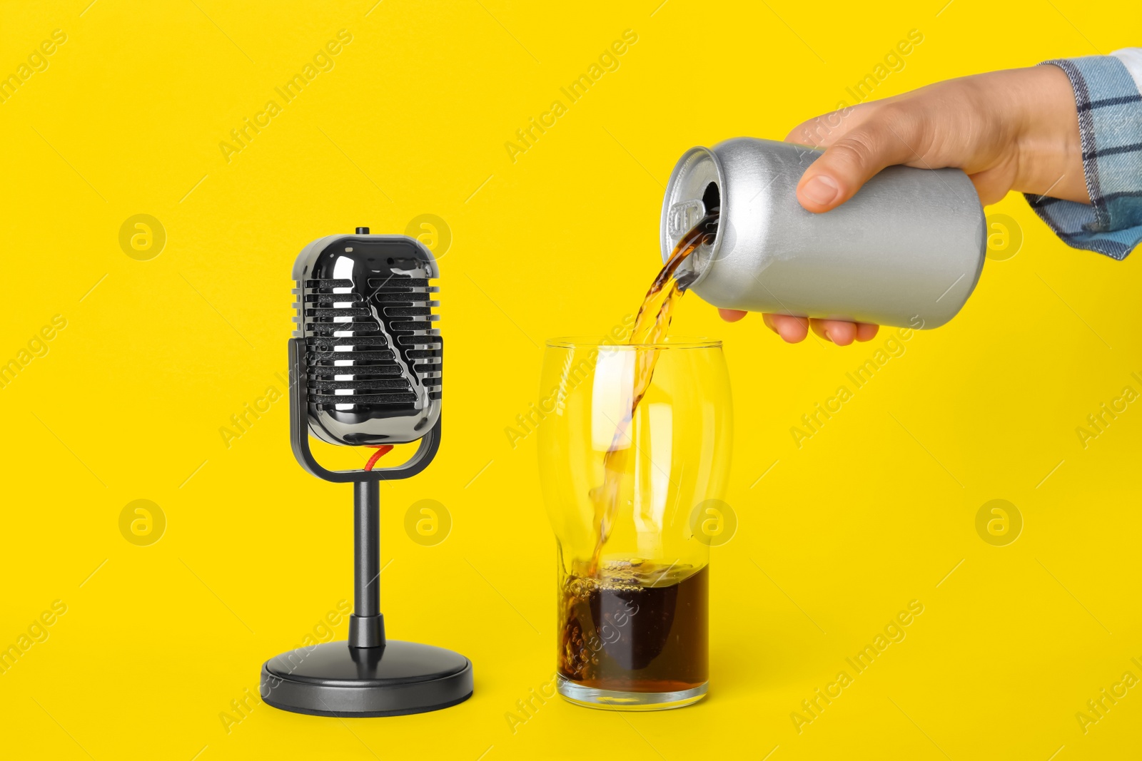 Photo of Woman making ASMR sounds with microphone and soda drink on yellow background, closeup