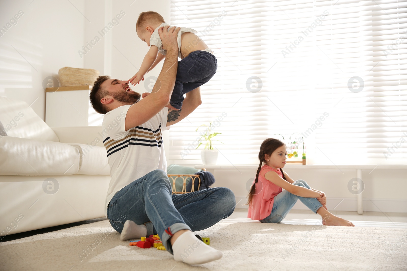 Photo of Unhappy little girl feeling jealous while father spending time with her baby brother at home