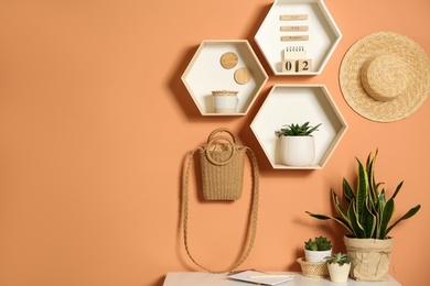 Shelves and table with decorative elements on color wall. Space for text