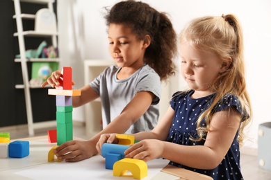 Cute little children playing with building blocks in kindergarten. Indoor activity