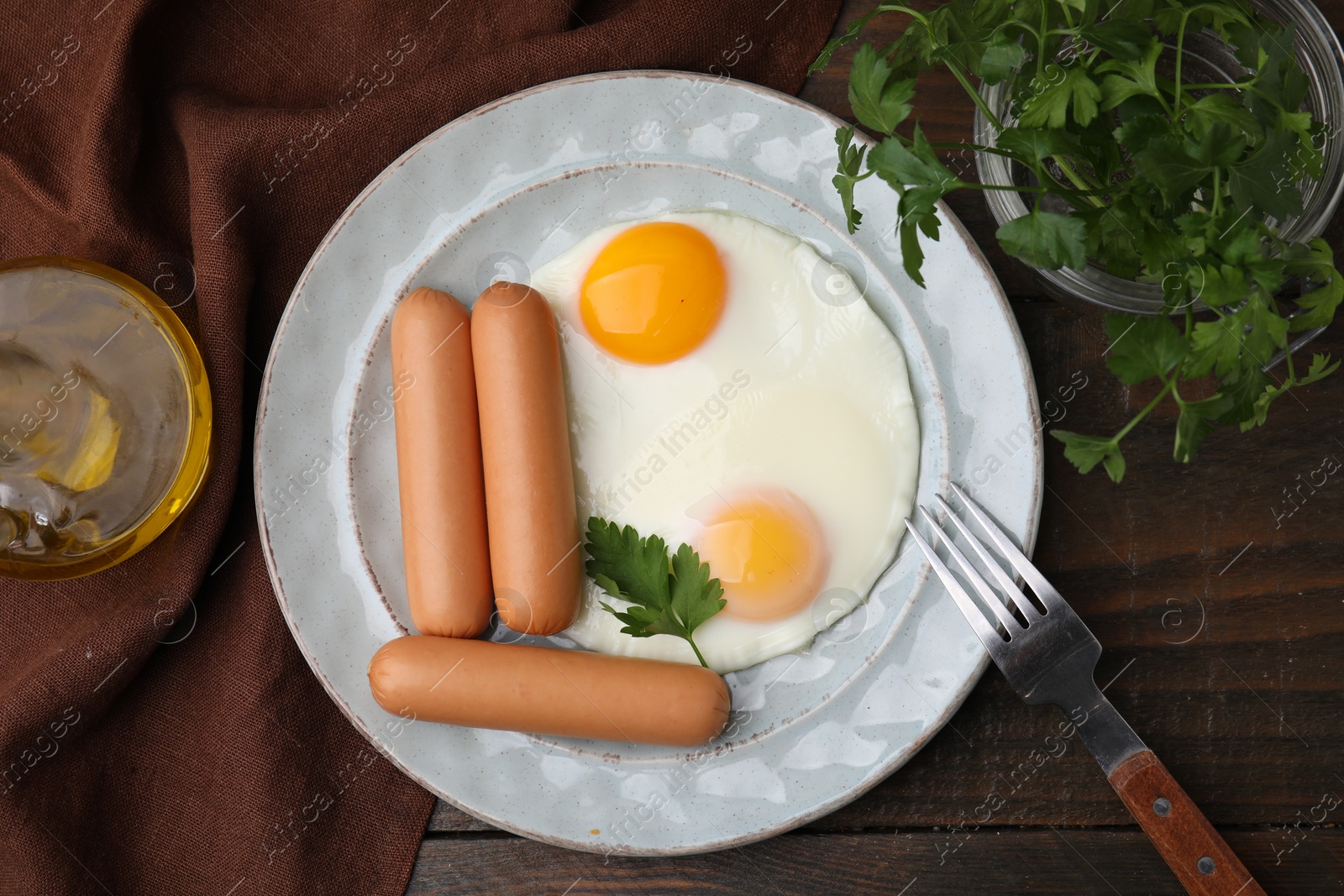 Photo of Delicious boiled sausages and fried eggs served on wooden table, flat lay