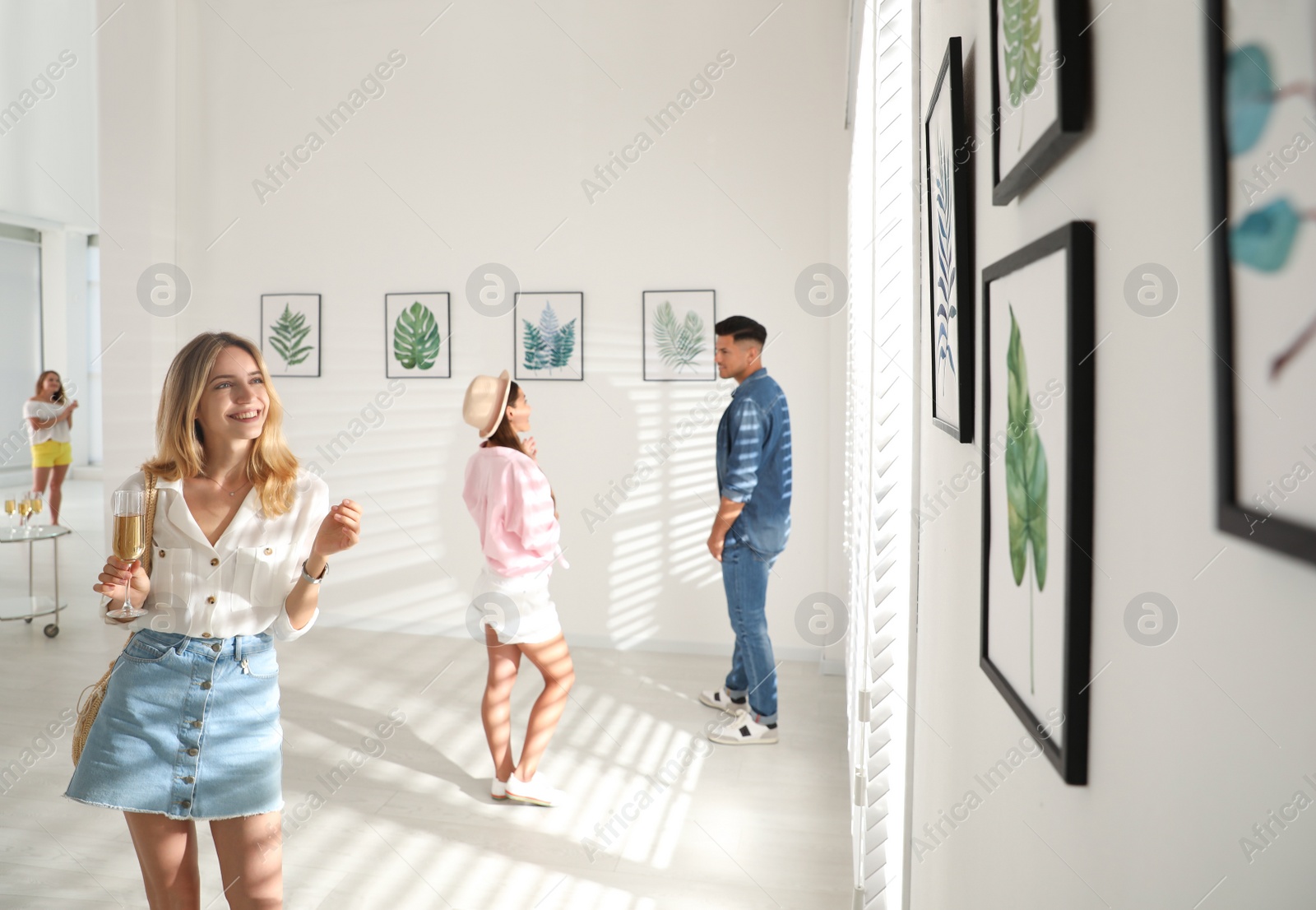 Photo of Young woman with glass of champagne at exhibition in art gallery