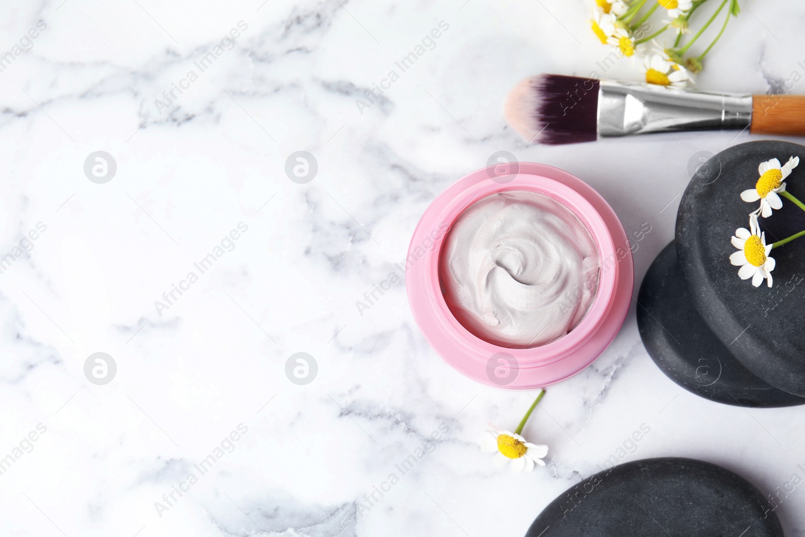 Photo of Professional face mask with brush, spa stones and flowers on white marble table, flat lay. Space for text