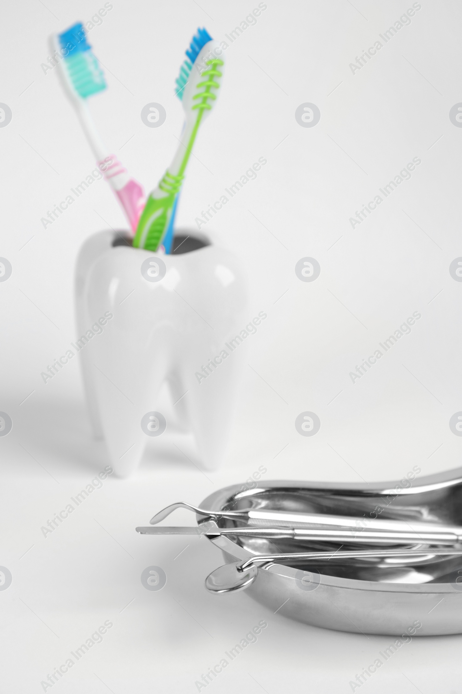Photo of Kidney shaped tray with set of dentist's tools on light background, closeup. Space for text