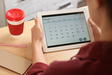 Photo of Woman using calendar app on tablet in office, closeup