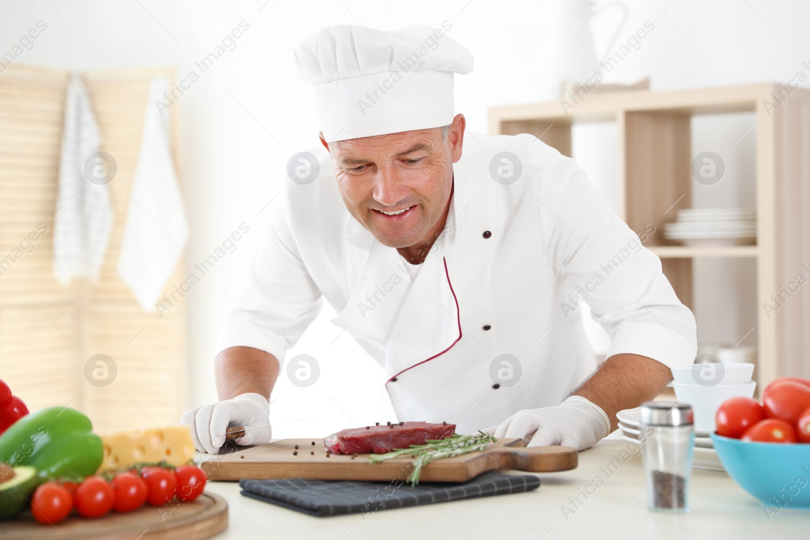 Photo of Professional chef cooking meat on table in kitchen