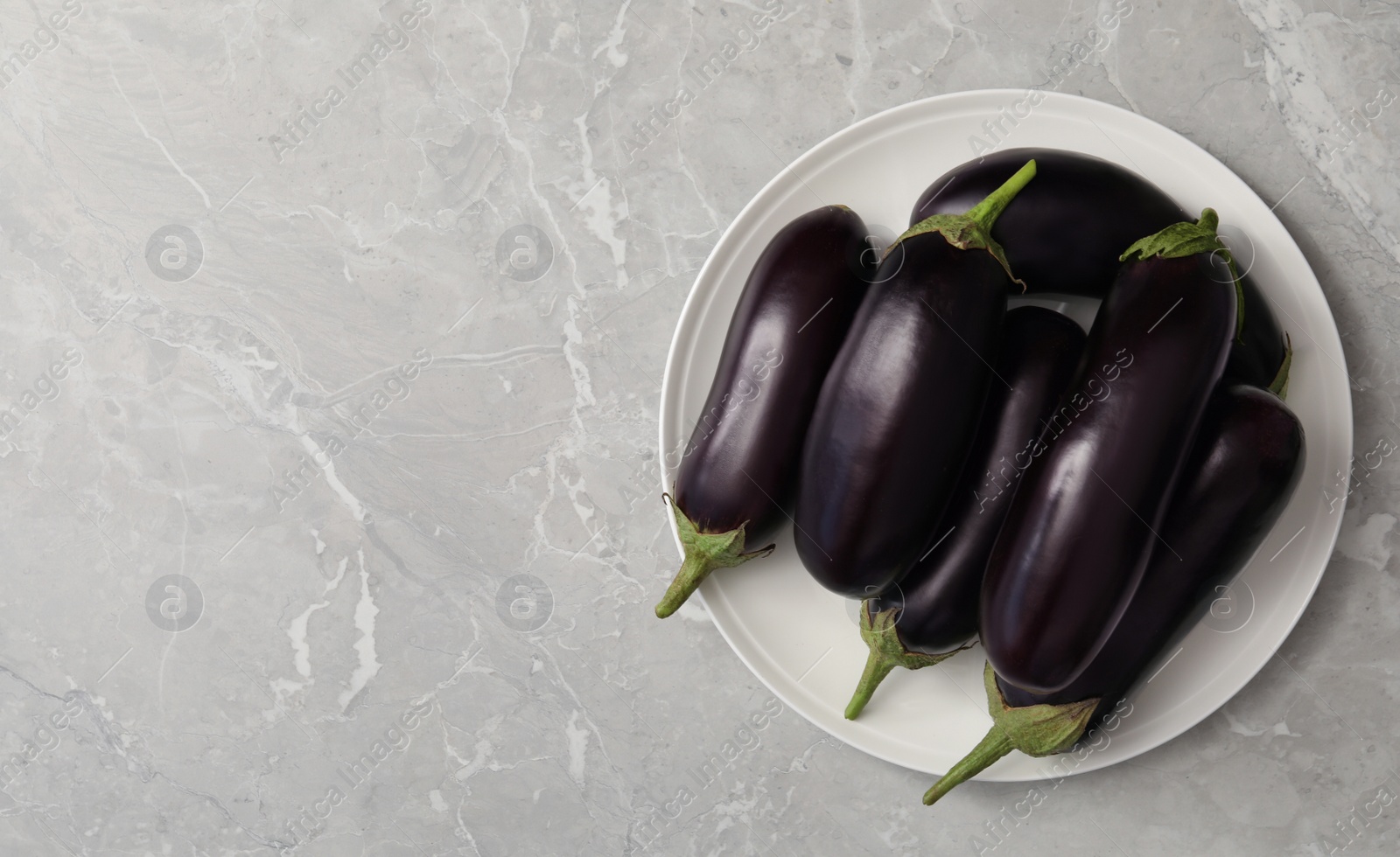 Photo of Raw ripe eggplants on grey table, top view. Space for text