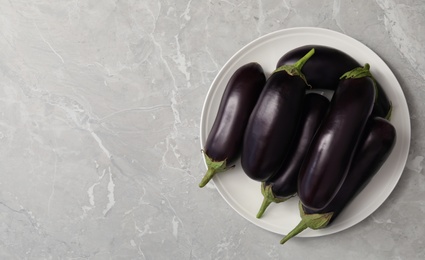 Photo of Raw ripe eggplants on grey table, top view. Space for text