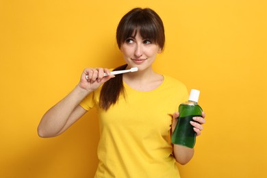 Photo of Young woman with mouthwash and toothbrush on yellow background