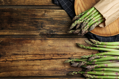 Photo of Fresh raw asparagus on wooden table, flat lay. Space for text