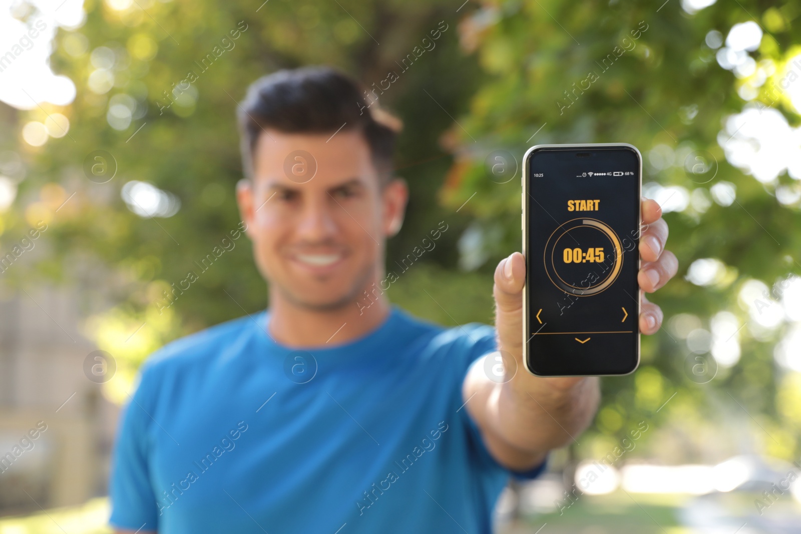Photo of Man showing smartphone with fitness app outdoors, focus on device