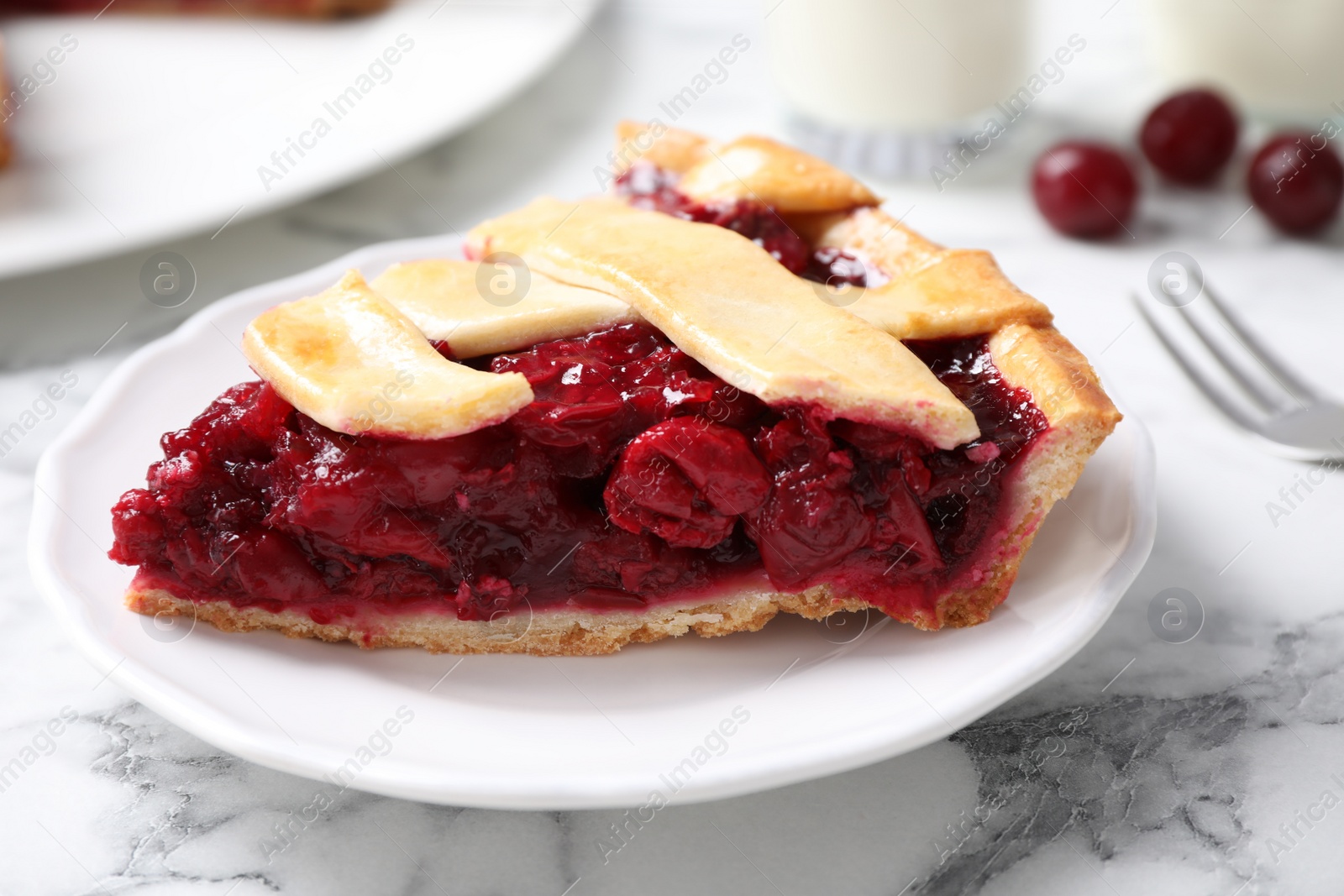Photo of Slice of delicious fresh cherry pie on white marble table, closeup