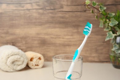 Photo of Toothbrush in glass on beige table, space for text