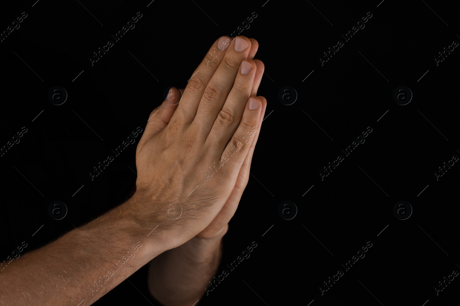 Photo of Man praying against black background, closeup view