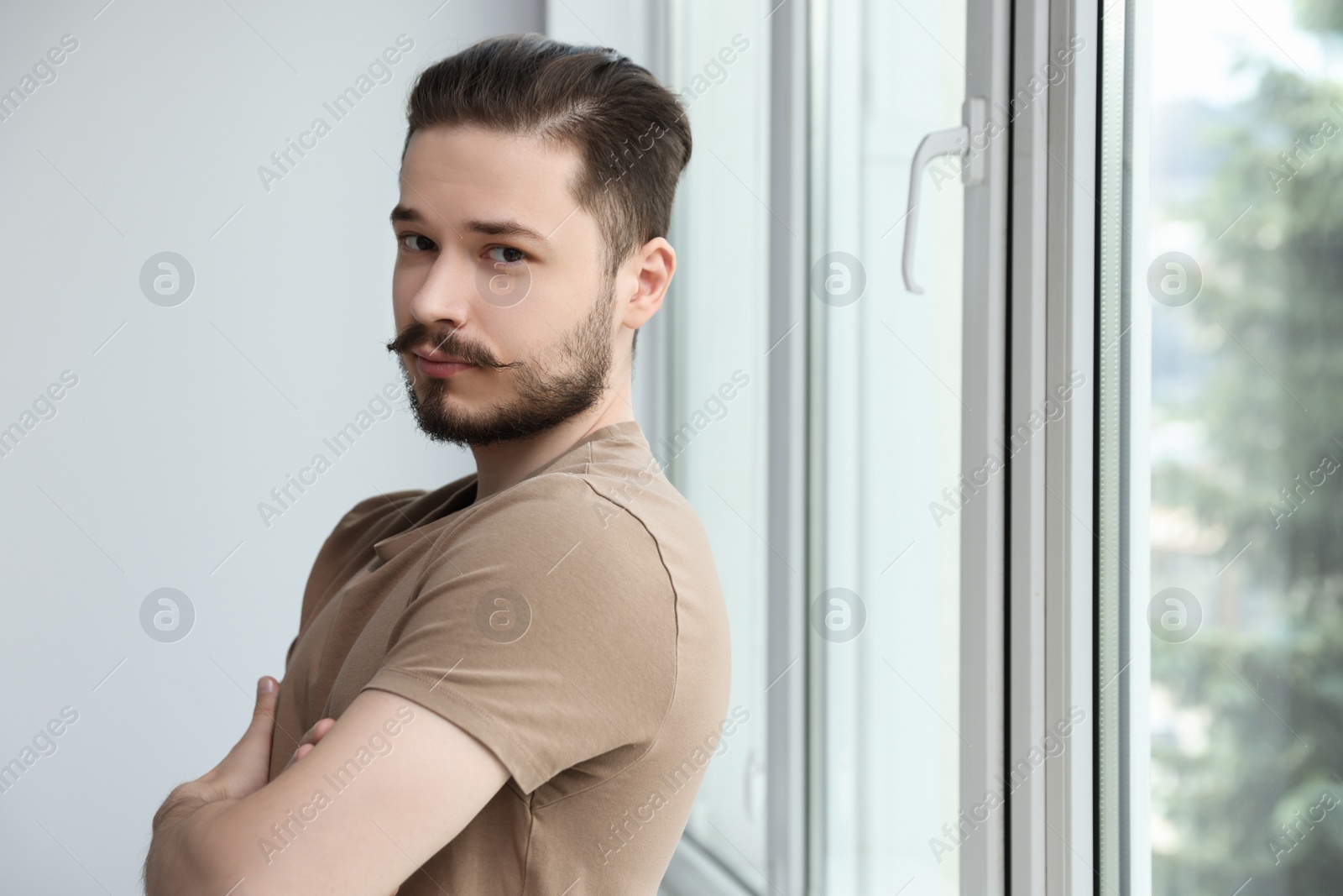 Photo of Handsome man near window indoors. Space for text