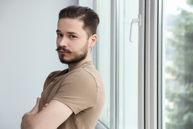 Photo of Handsome man near window indoors. Space for text