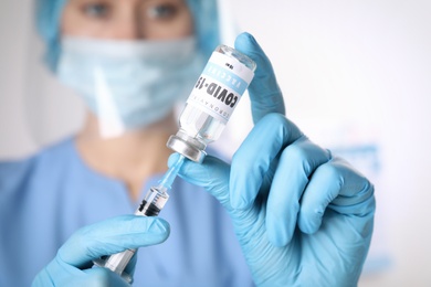 Doctor filling syringe with vaccine against Covid-19 indoors, closeup