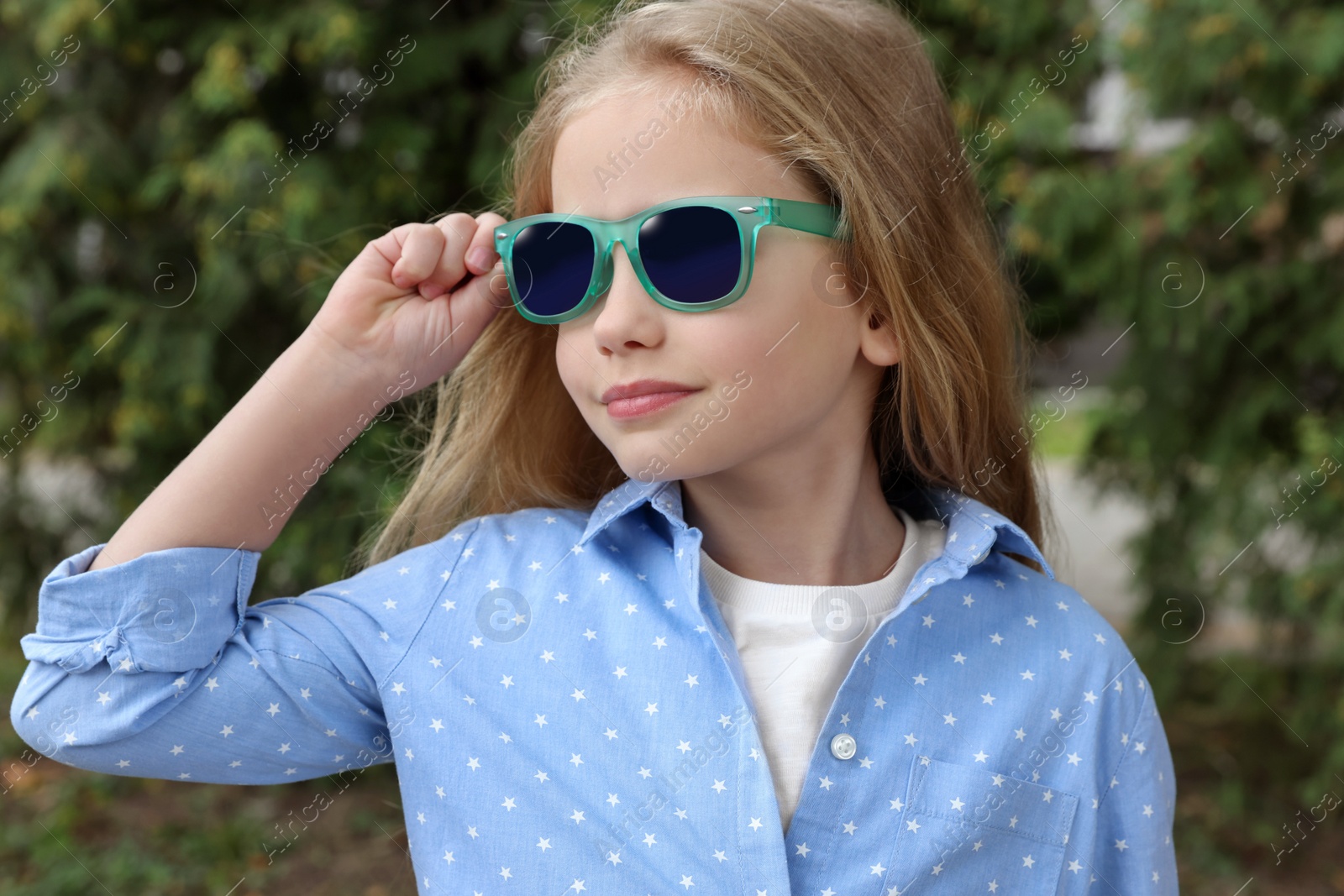 Photo of Girl in stylish sunglasses near spruce trees outdoors