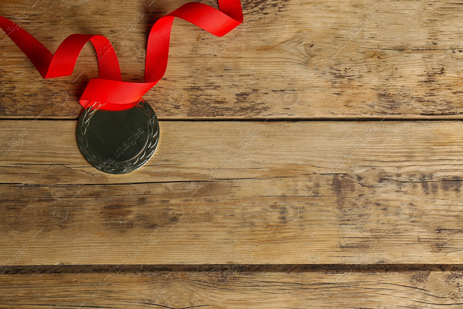 Photo of Medal with red ribbon on wooden background, top view. Space for design