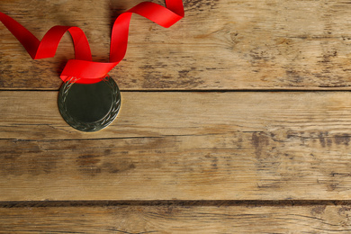 Medal with red ribbon on wooden background, top view. Space for design