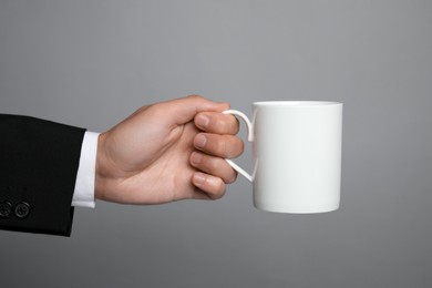 Photo of Man holding white mug on gray background, closeup