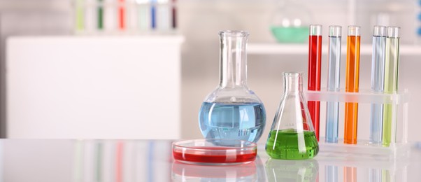 Photo of Laboratory analysis. Different glassware with liquids on white table against blurred background. Space for text