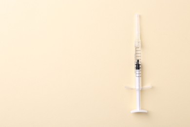 Photo of Injection cosmetology. One medical syringe on beige background, top view. Space for text