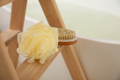 Photo of Sponge and brush on wooden stand near tub