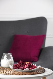 Photo of Aromatic potpourri of dried flowers and burning candle on table indoors