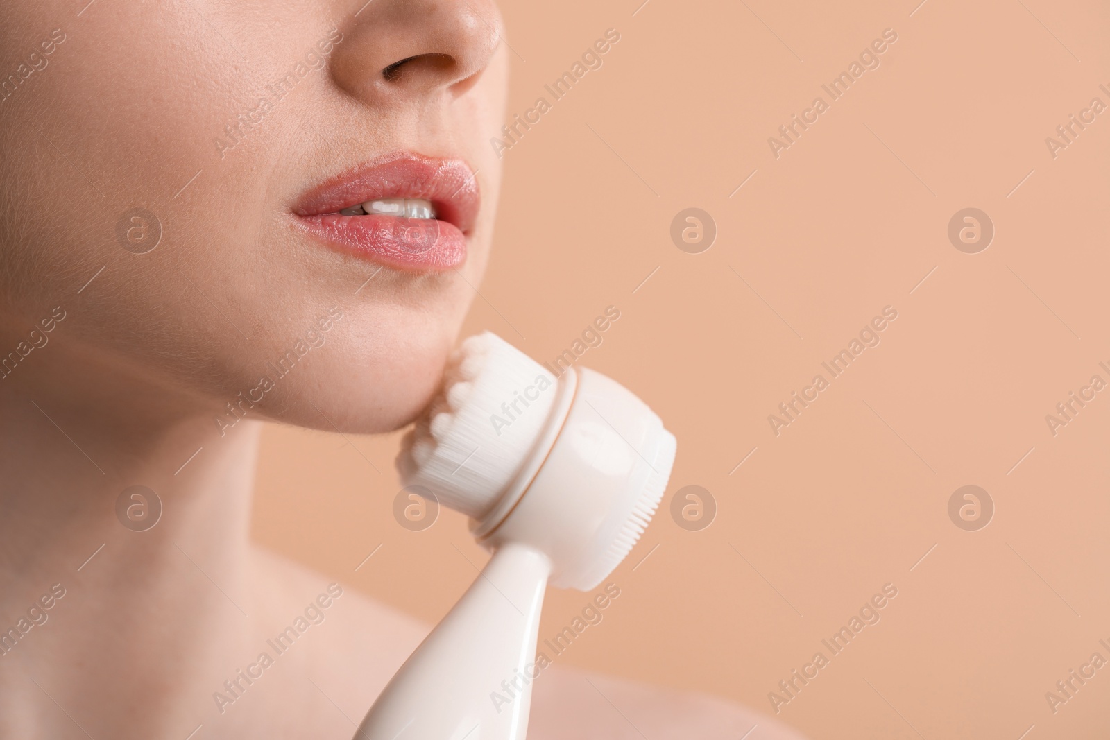 Photo of Washing face. Young woman with cleansing brush on beige background, closeup. Space for text