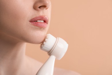 Photo of Washing face. Young woman with cleansing brush on beige background, closeup. Space for text