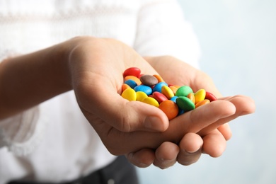 Photo of Woman holding glazed candies on light background, closeup