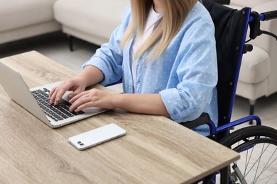 Photo of Woman in wheelchair using laptop at home, closeup