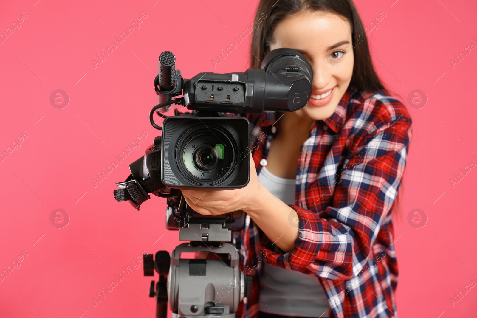 Photo of Operator with professional video camera on pink background