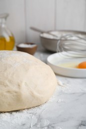 Photo of Fresh yeast dough with flour on white marble table, closeup