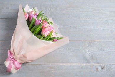 Photo of Bouquet of beautiful tulips on grey wooden table, top view. Space for text