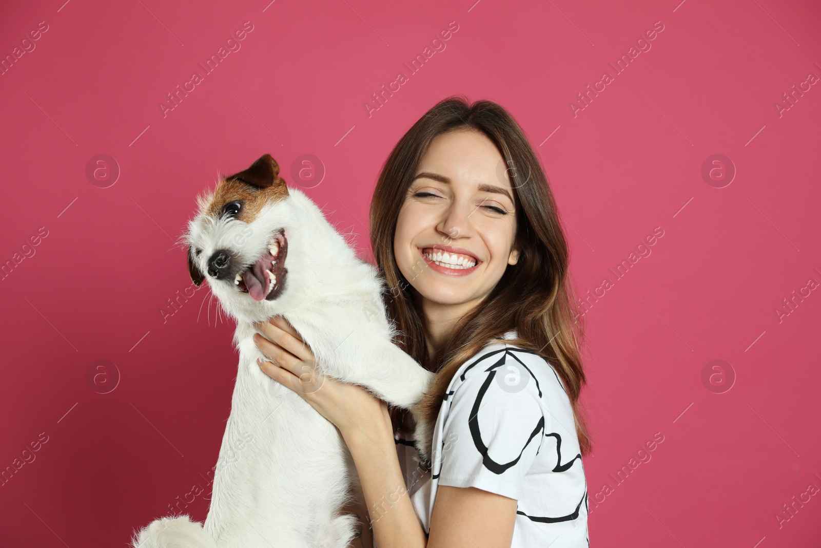 Photo of Young woman with her cute Jack Russell Terrier on pink background. Lovely pet