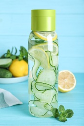 Bottle of refreshing water with cucumber, lemon and mint on light blue wooden table